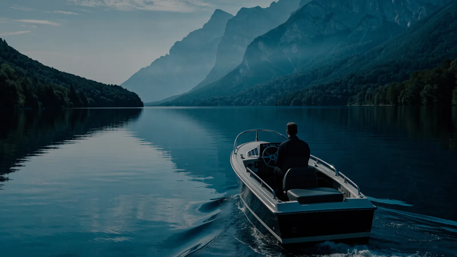 Motorboot auf einem ruhigen Bergsee, dahinter bewaldete Hänge