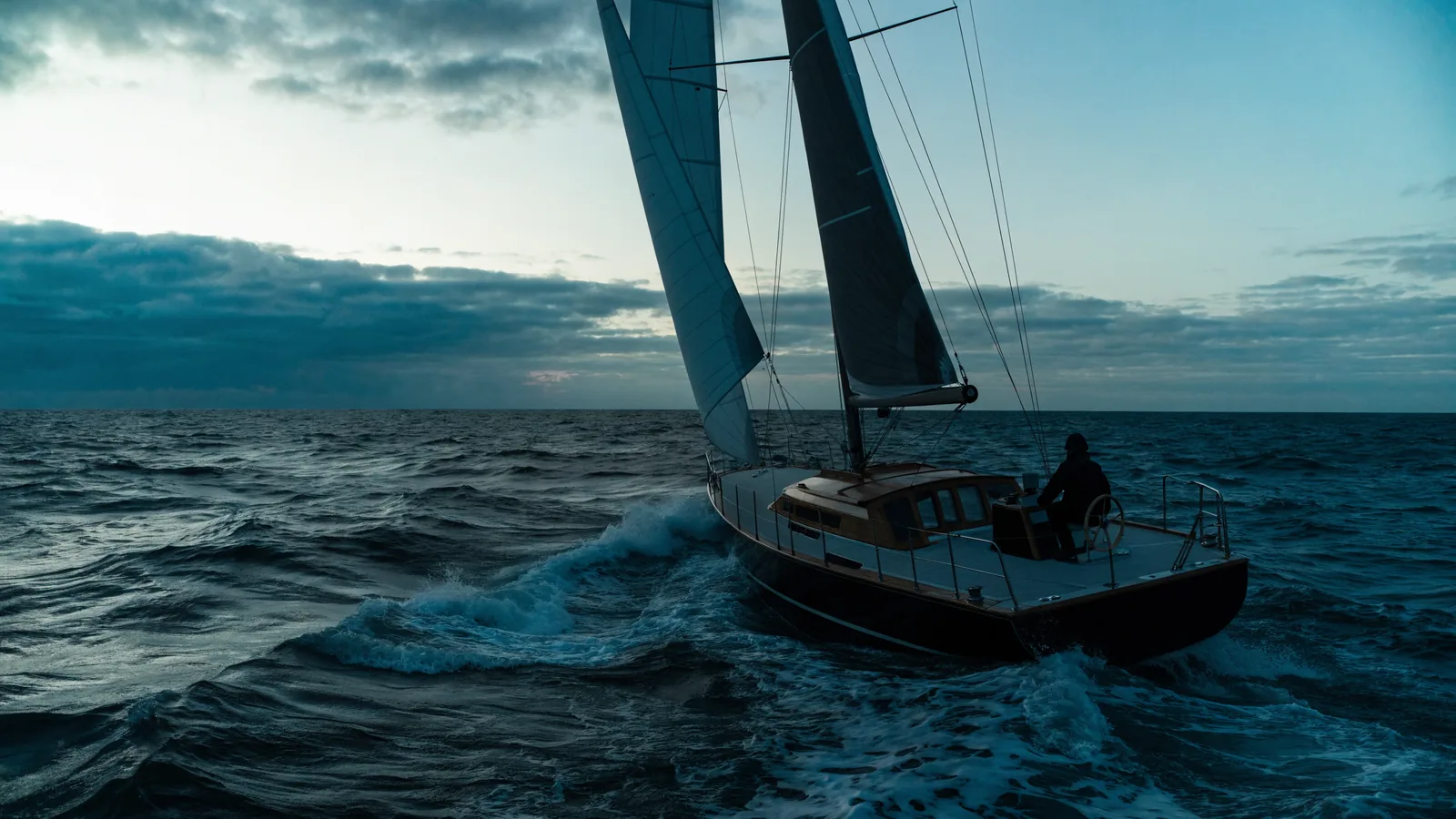 Segelyacht in grober See, der Steuermann am Rad