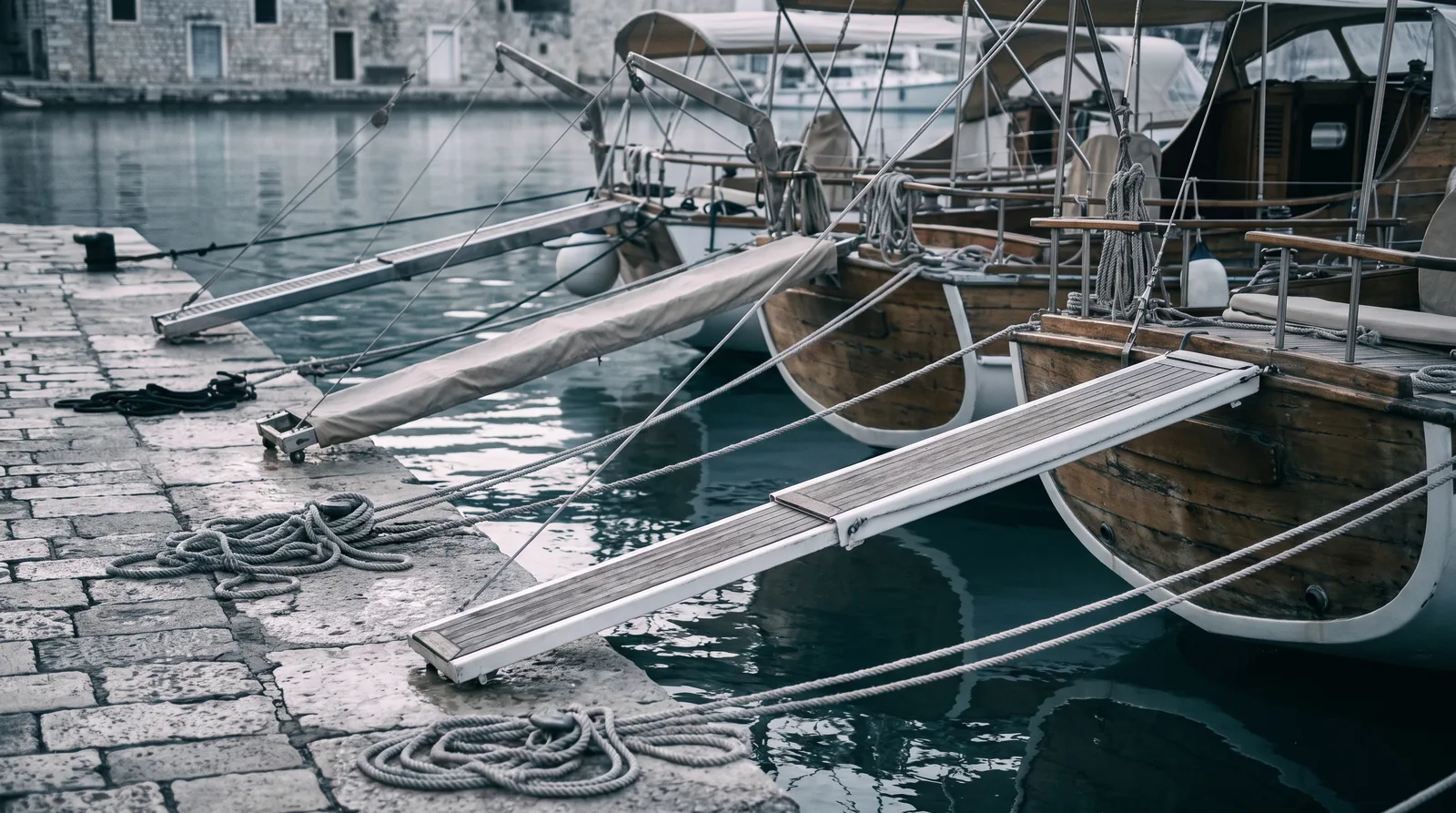 Eine Reihe Yachtheckansichten am Steinkai, die Gangways liegen auf dem Stein