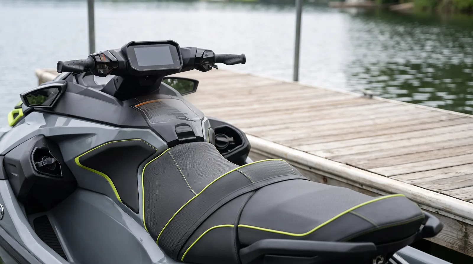 Lenker und lange graue Sitzbank eines modernen Jetskis am Holzsteg, der See im Hintergrund unscharf.