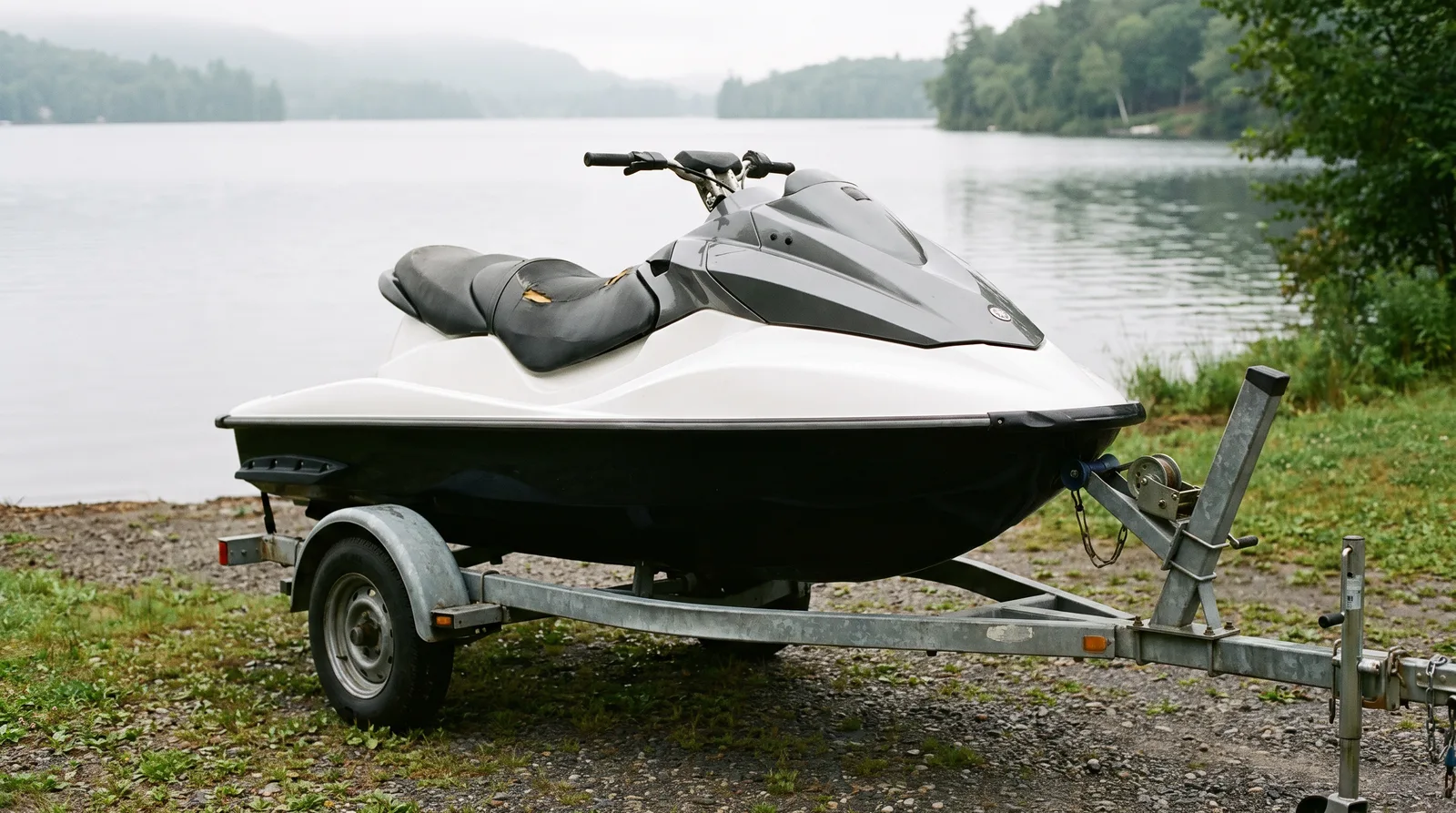 Sportjetski in Weiß und Dunkelgrau auf einem Trailer am Seeufer.
