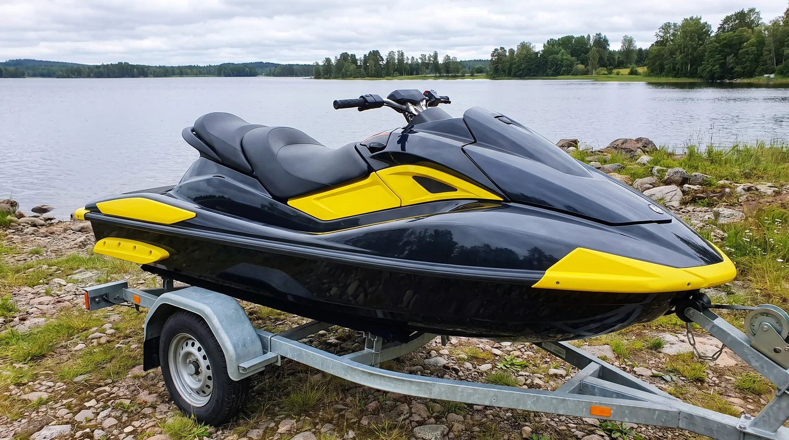 Sportjetski in Schwarz und Gelb auf einem Trailer am Seeufer.