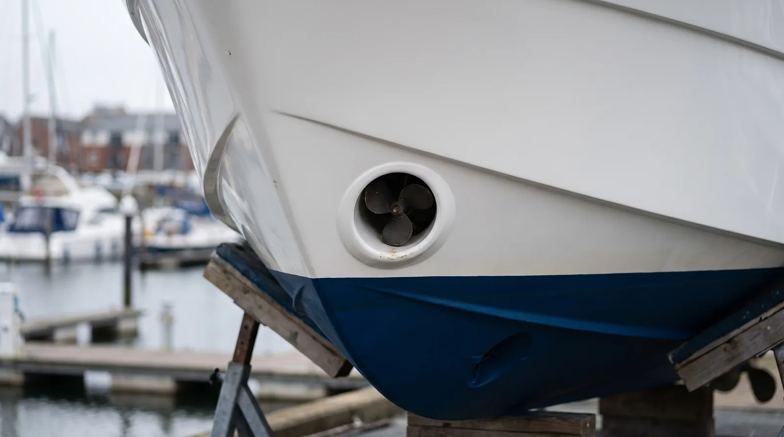 Bug einer gepflegten Motoryacht an Land mit der runden Öffnung des Bugstrahlruders und dem kleinen Propeller im Tunnel