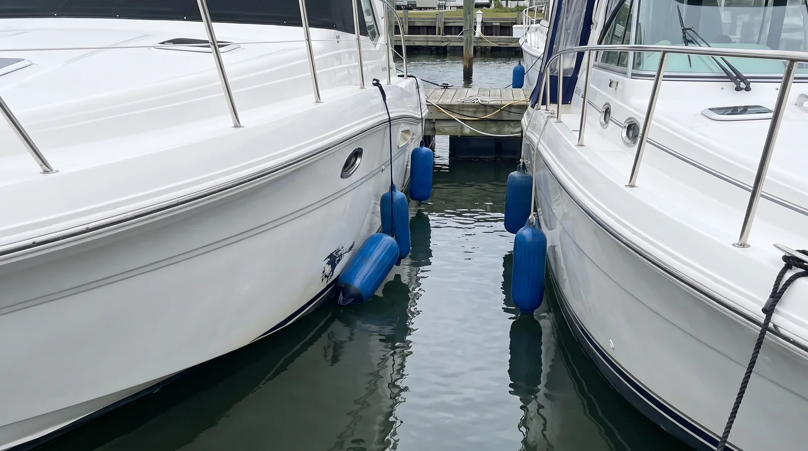 Zwei Motorboote dicht nebeneinander im Hafen, Fender zwischen den Rümpfen
