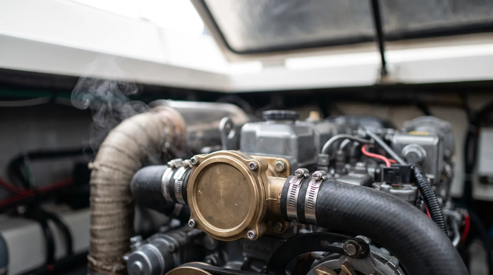 Gepflegter Dieselmotor im Motorraum einer Motoryacht mit Seewasserpumpe, Kühlwasserschlauch und Schlauchschellen im Vordergrund