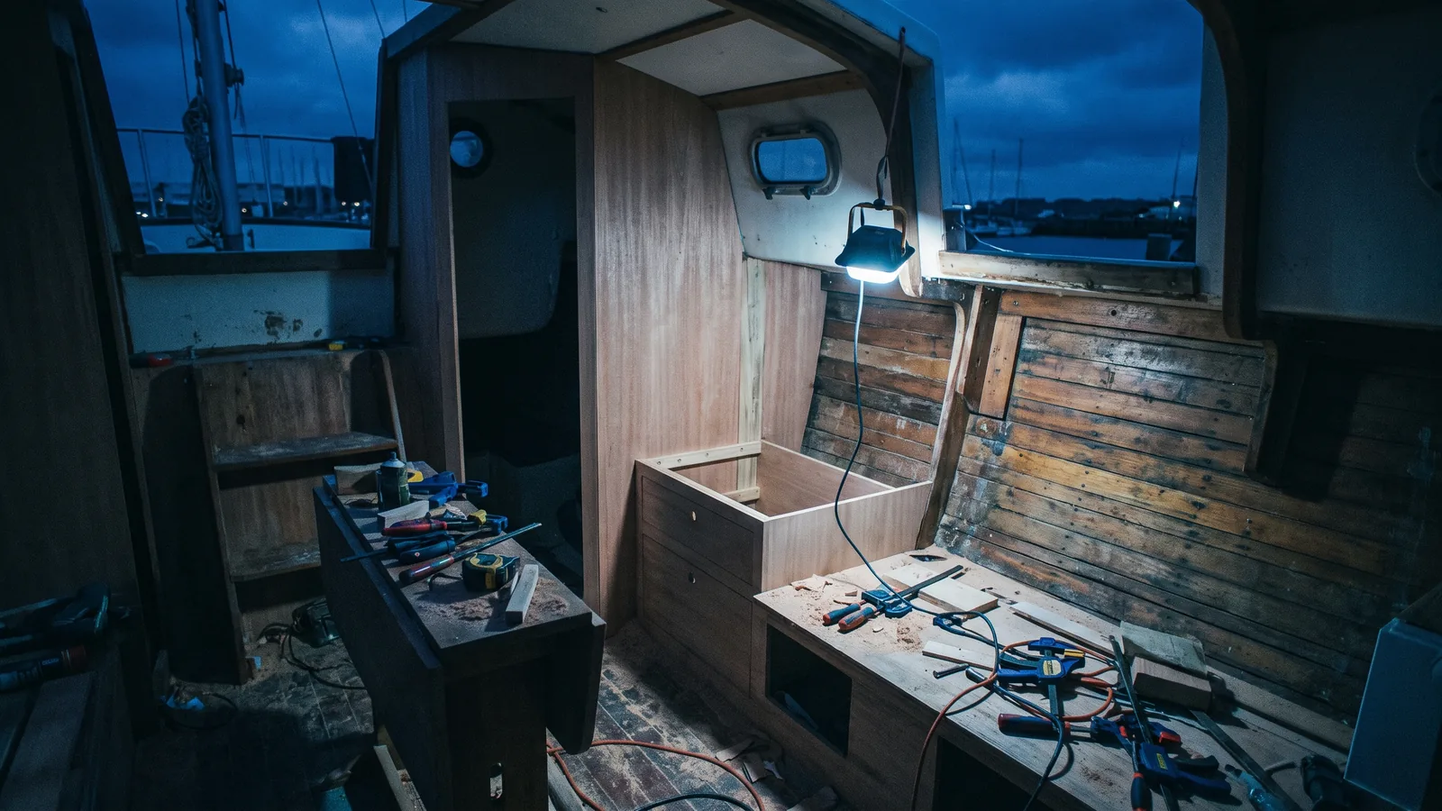 Bootsinnenraum im Umbau bei Nacht, frische Tischlerarbeit neben alter Vertäfelung