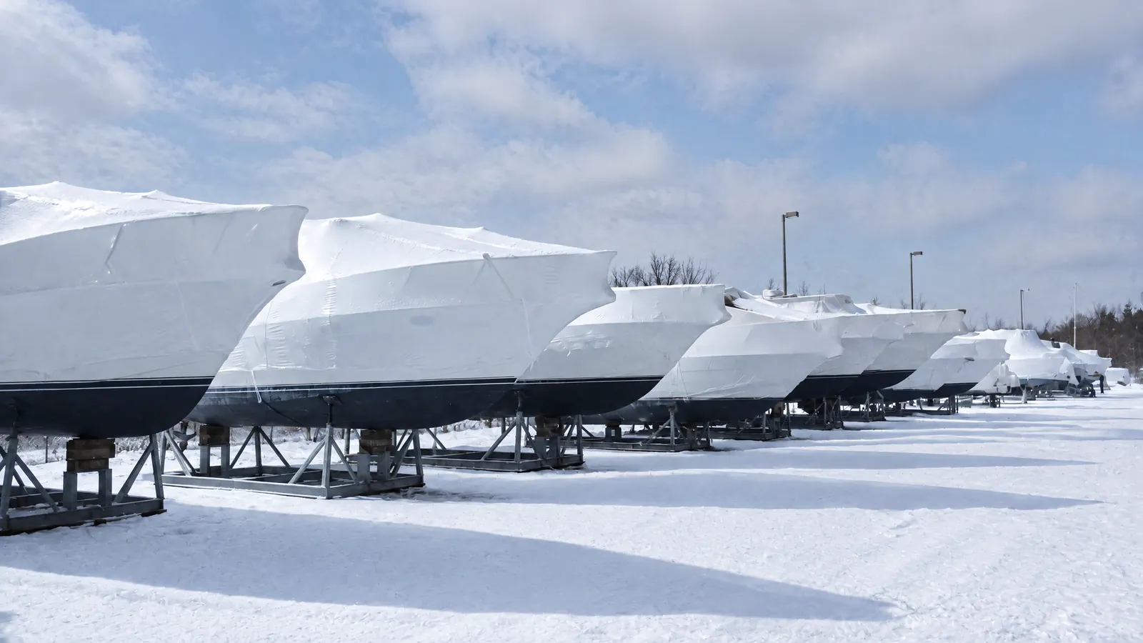 Eingewinterte Boote auf Böcken in einer Lagerhalle, die Planen frisch gespannt